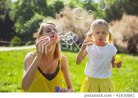 Cheerful mommy blowing bubbles wither daughter 41630861