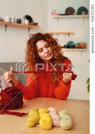 Ginger-haired girl wearing red sweater holding crochet thread Ginger-haired girl wearing red sweater holding crochet thread 41633260
