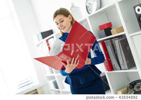 A young girl stands in the office near the shelter and holds a folder with documents in her hands. 41634892