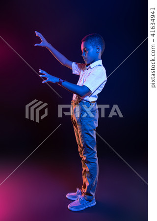 Unsmiling little boy adjusting some buttons Unsmiling little boy adjusting some buttons 41634941