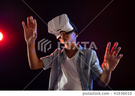 Concentrated teenager wearing a modern VR headset 41636010