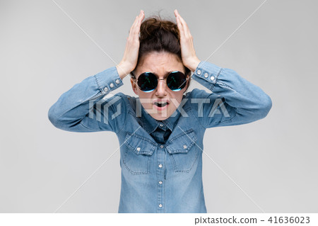 Young brunette girl in round glasses. Hairs are gathered in a bun. The girl holds her hands behind 41636023