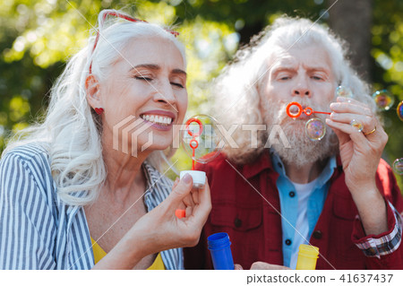Delighted aged woman looking at the soap bubble Delighted aged woman looking at the soap bubble 41637437