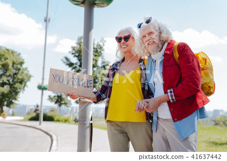 Happy elderly couple hitchhiking 41637442