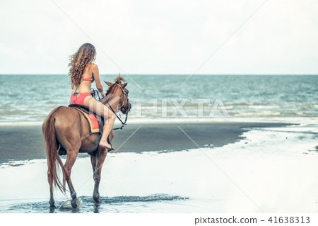 Woman fashion model riding a horse on the beach. Woman fashion model riding a horse on the beach. 41638313