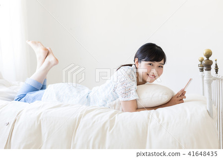 A young lady watching a smartphone lying on the bed 41648435