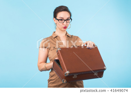 Portrait of excited young woman holding a suitcase isolated over blue background, Travel, holidays Portrait of excited young woman holding a suitcase isolated over blue background, Travel, holidays 41649074
