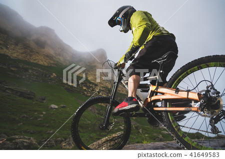 Extreme mountain bike sports athlete man in helmet riding outdoors against a background of rocks 41649583