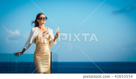 Woman drinking sparkling wine looking over ocean 41653554
