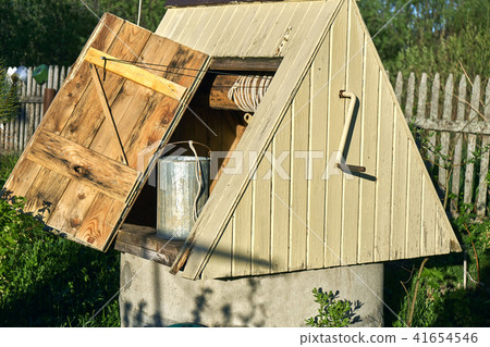 Wooden draw-well with a metal bucket at countryside in summer day 41654546