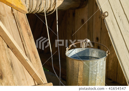 Metal bucket full of fresh water just taken up from a old wooden draw-well at countryside in a 41654547