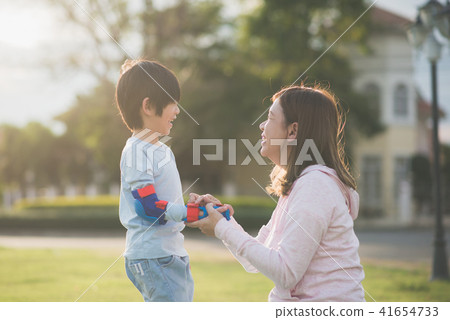 mother helping her son putting hand protectors mother helping her son putting hand protectors 41654733