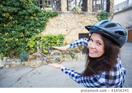 Young woman with helmet posing on bicycle and alley background Young woman with helmet posing on bicycle and alley background 41656345