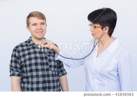 healthcare, medical exam, people and medicine concept - young man and doctor with stethoscope healthcare, medical exam, people and medicine concept - young man and doctor with stethoscope 41656563