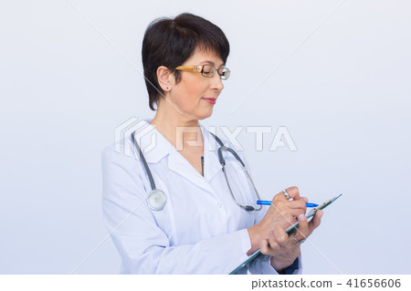 Portrait Of Female Doctor Writing On Clipboard Over a white background Portrait Of Female Doctor Writing On Clipboard Over a white background 41656606