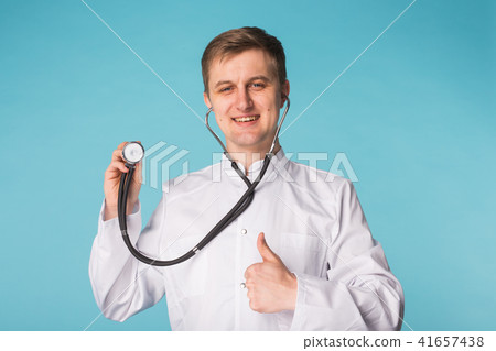 Doctor with stethoscope showing thumbs up over blue background 41657438