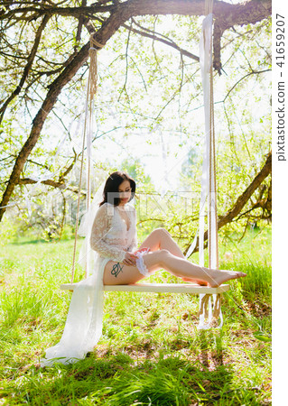 Seductive young bride on a white rope swing dressing garter 41659207