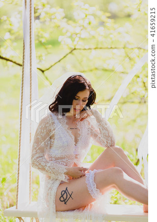 Young sexy bride on a white rope swing dressing garter 41659215