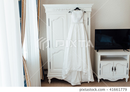 Wedding dress hanging on the cupboard Wedding dress hanging on the cupboard 41661779