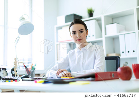 A young girl is sitting at the computer desk in the office. 41662717