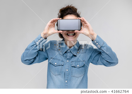 Young brunette girl in round glasses. Hairs are gathered in a bun. Girl with a black phone. The girl Young brunette girl in round glasses. Hairs are gathered in a bun. Girl with a black phone. The girl 41662764