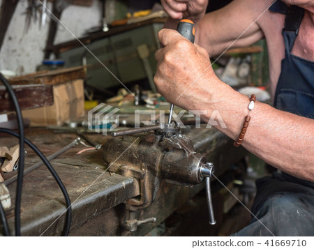 Older man sitting at workbench and working. Human 41669710