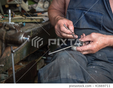 Man with hand tools sitting at the home workbench 41669711