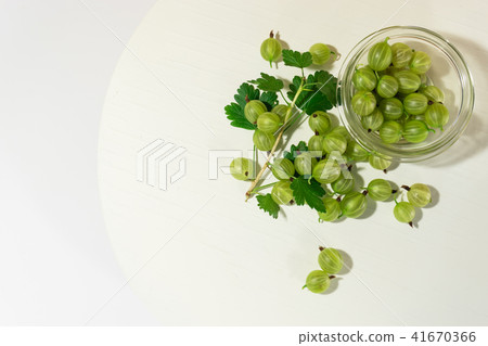 Green gooseberry on a round wooden table.  41670366