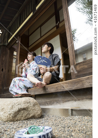 在yukata的兩三對男性和女性夫婦吃西瓜的在一個老私有房子一邊 在yukata的兩三對男性和女性夫婦吃西瓜的在一個老私有房子一邊 41671469