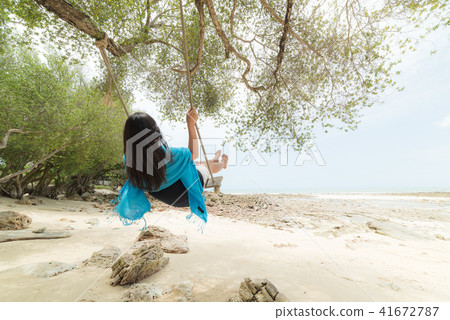 woman relaxing on wooden swing under tree 41672787