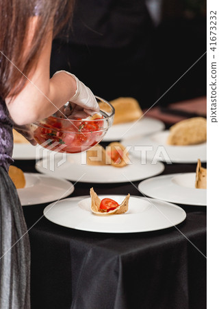 Hand of a girl puts tomato in tacos. The chef at the restaurant is going to make Spicy Shrimp Tacos 41673232
