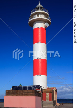 Lighthouse on beach against blue sky 41675789