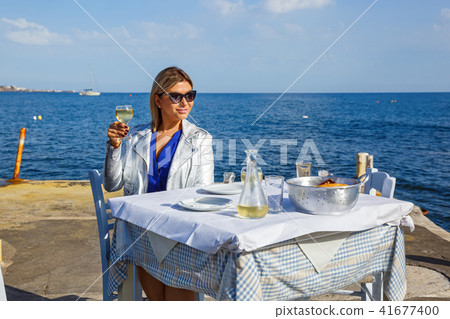 Young woman in a restaurant by the sea Young woman in a restaurant by the sea 41677400