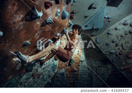 Free climber young man climbing artificial boulder indoors Free climber young man climbing artificial boulder indoors 41680437