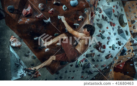 Free climber young man climbing artificial boulder indoors 41680463