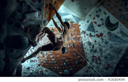 Free climber young man climbing artificial boulder indoors 41680494
