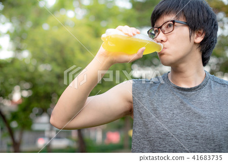 Young Asian man runner drinking energy drink Young Asian man runner drinking energy drink 41683735