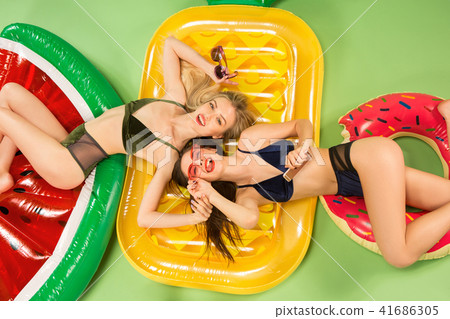 Cute girls in swimsuits posing at studio. Summer portrait caucasian teenagers on green background. Cute girls in swimsuits posing at studio. Summer portrait caucasian teenagers on green background. 41686305