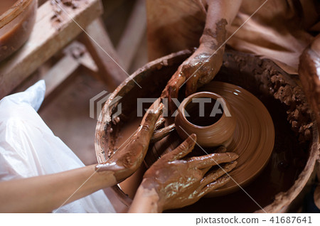 Hands working on pottery wheel. Close up of Ceramist hands at work in her workshop Hands working on pottery wheel. Close up of Ceramist hands at work in her workshop 41687641
