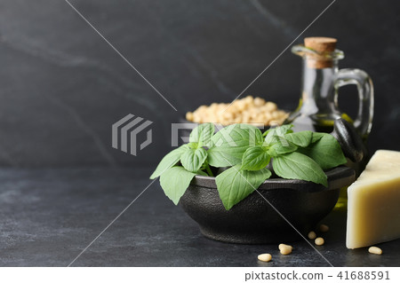 Basil leaves, parmesan cheese and other pesto sauce ingredients on black 41688591