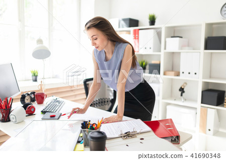 Beautiful Young girl in an office is standing near a table and draws a marker on a magnetic board. 41690348