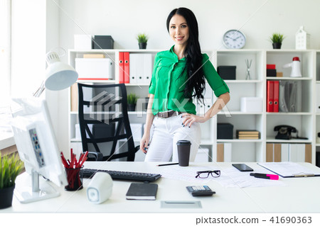 A young girl stands near an office desk. 41690363