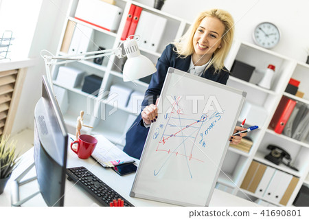 A young girl stands near a table in the office and explains the schedule on the magnetic board. A young girl stands near a table in the office and explains the schedule on the magnetic board. 41690801