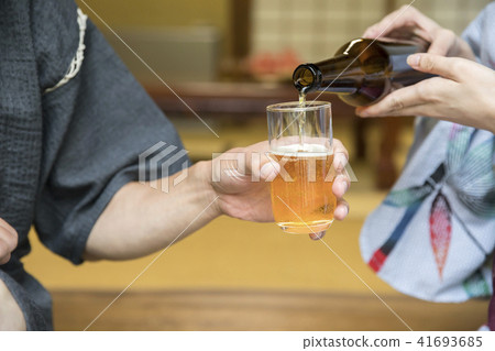 在老私有房子女性手的邊緣的Yukata傾吐的啤酒 在老私有房子女性手的邊緣的Yukata傾吐的啤酒 41693685