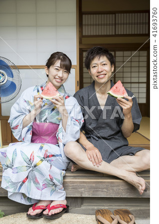 A couple of male and female couples in a yukata eating watermelon on the side of an old private house A couple of male and female couples in a yukata eating watermelon on the side of an old private house 41693760