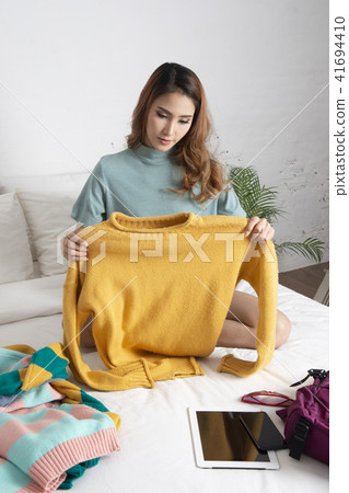 Woman packing her clothes for journey on bed. Woman packing her clothes for journey on bed. 41694410
