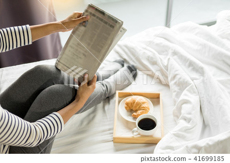 Woman reading book or newspaper and drinking coffee breakfast on 41699185