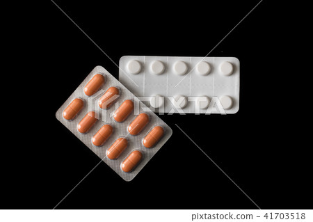 White and orange pills on a black background White and orange pills on a black background 41703518