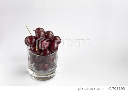 Red cherries in a clear glass on  light background 41705893