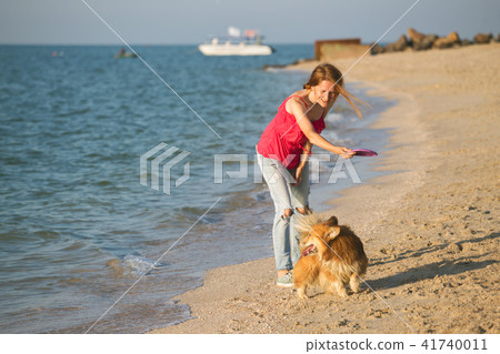 girl playing with a dog on the beach 41740011